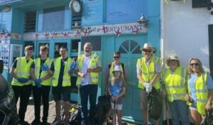 A group of about ten litter pickers in high viz jackets standing in front of Bennett's fish and chip shop